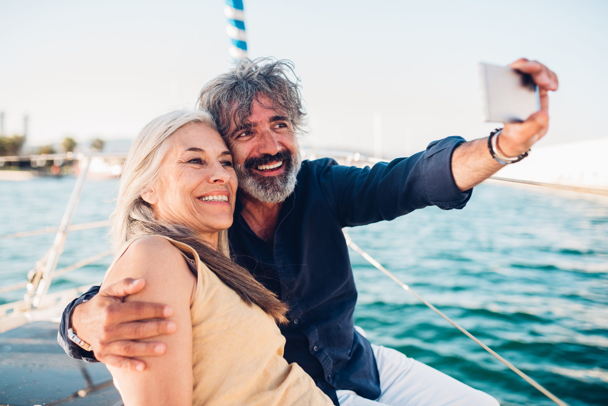 Senior couple taking a selfie while cruising on their yacht.