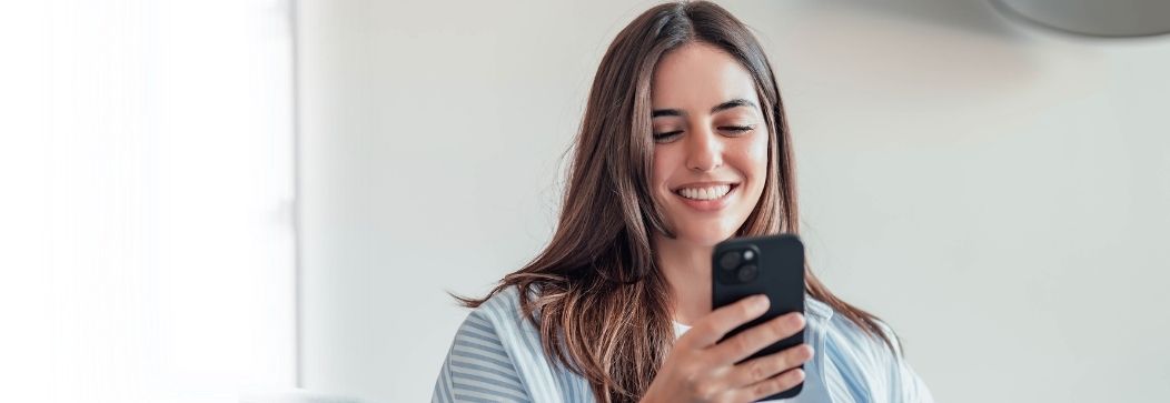 Woman smiling while using her smartphone